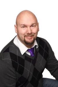 Jesse Lewis smiling in a sweater with purple tie – professional comedy hypnotist headshot