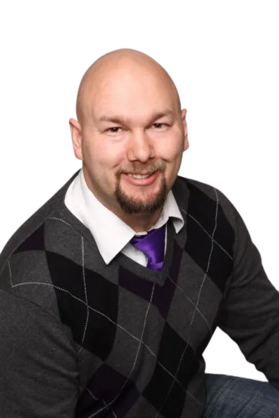 Jesse Lewis smiling in a sweater with purple tie – professional comedy hypnotist headshot